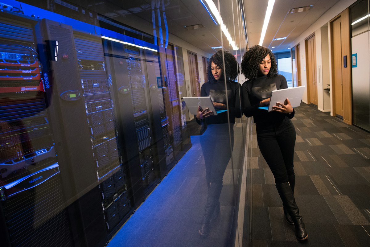 An engineer working on a tablet in a data centre, reflected in the glass of the server racks